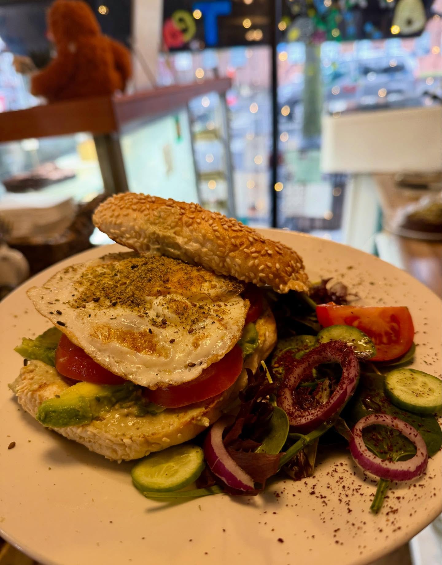 Sesame bagel with fried egg, avocado and salad