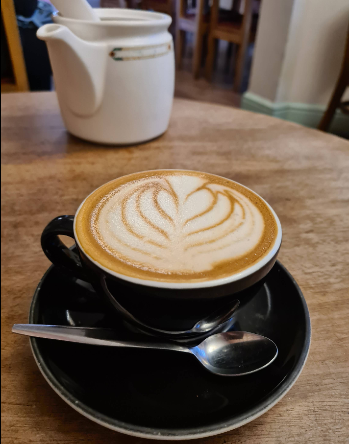 Flat white with latte art on a black saucer