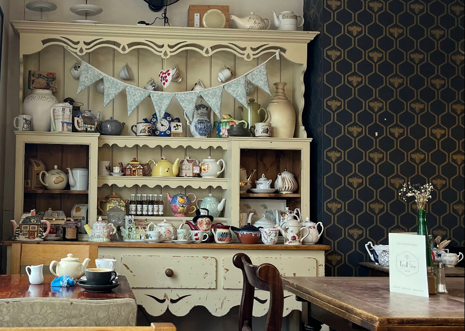 Vintage dresser stacked with teapots and bee wallpaper